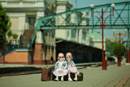 Vintage looking picture of small girls with luggage at the railway stationの写真素材