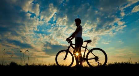 Biker-girl at the sunset on the meadowの写真素材