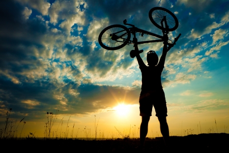 Biker holds bike high up in the skyの写真素材