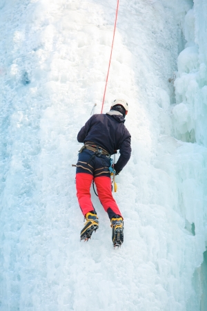 Man climbing frozen waterfallの写真素材