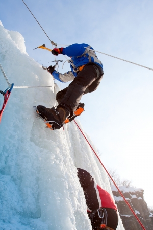 Man climbing frozen waterfallの写真素材