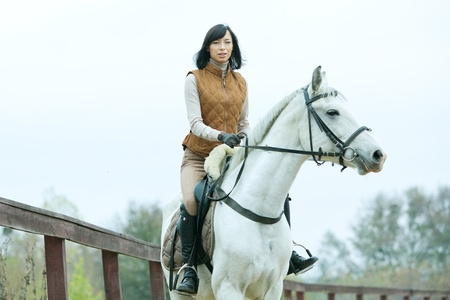 Woman jockey is riding the horse outdoorの写真素材