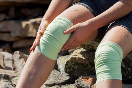 Athlet looking girl fixes bandage on knees outdoor