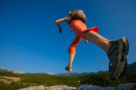 Hiker jumps over the rockの写真素材