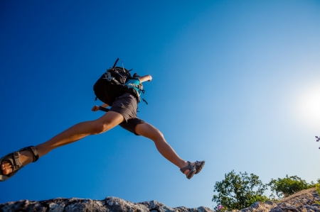 Hiker jumps over the rockの写真素材