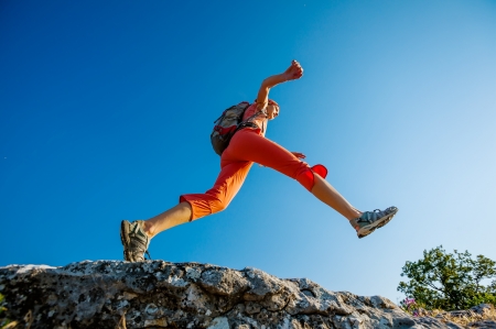 Hiker jumps over the rockの写真素材