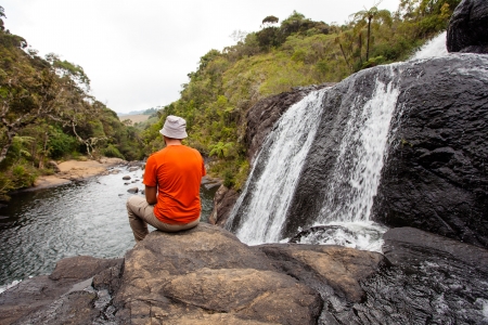 Trekker looks at wild waterfall in Horton Plains National Park, Sri Lankaの写真素材