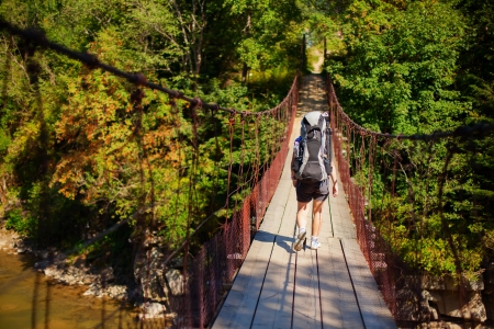 Woman hiker goes through suspension bridgeの写真素材