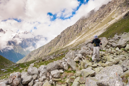 Hikier is jumping on rocks in Caucasus mountains in Bezengi region, Kabardino-Balkaria, Russiaの写真素材