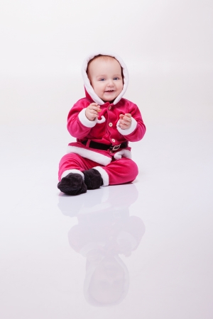 Small boy in Santa suit plays in white studioの写真素材