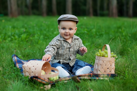 Happy child with basket of fruits playing outdoors in autumn parkの写真素材