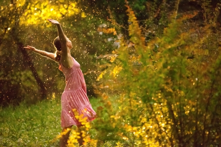 pretty young woman under summer rain during a beautiful sunsetの写真素材
