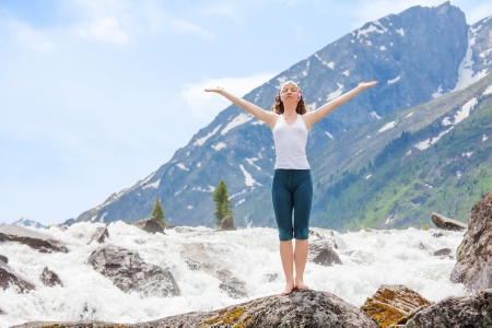 Young woman is practicing yoga at mountain riverの写真素材