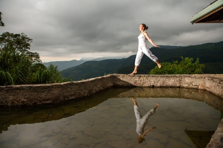 Woman walks by pool in mountain during cloudy dayの写真素材