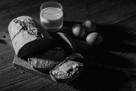 Bread with butter and eggs at the woodent table in low-light styleの写真素材
