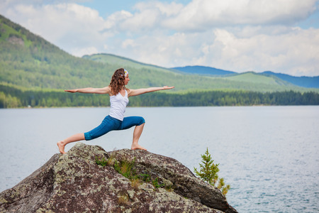 Young woman is practicing yoga at mountain lakeの写真素材
