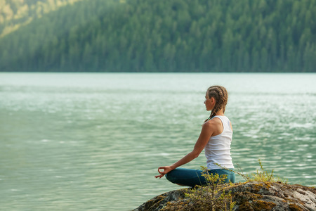 Young woman is practicing yoga at mountain lakeの写真素材