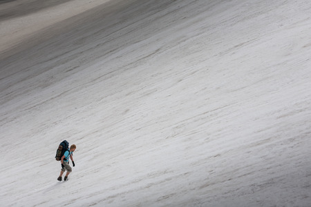 Backpacker passes snow field in rocky mountain in Altai mountains, Russiaの写真素材