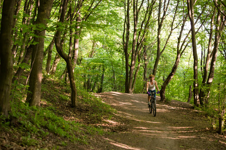 Woman is cycling in spring forestの写真素材
