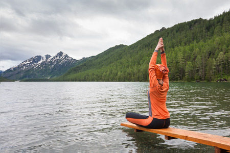 Woman is doing yoga at Multinskoe lake in Altai mountains, russiaの写真素材