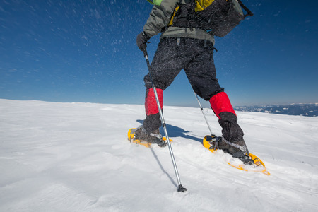 Hiker snowshoeing in winter mountains during sunny dayの写真素材