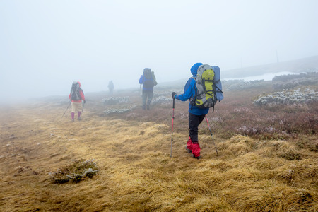 Group of hiker are walking in mountains covered with dense clouds