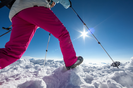 Hiker posing at top of snowy mountain during sunny dayの写真素材