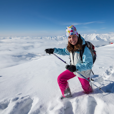 Hiker posing at top of snowy mountain during sunny dayの写真素材