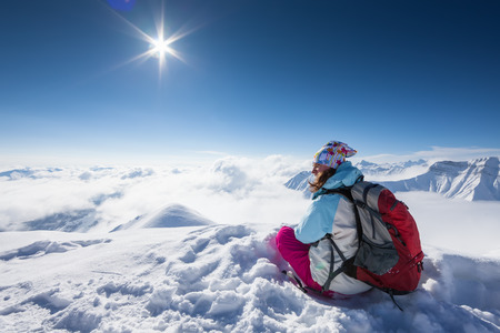Hiker posing at top of snowy mountain during sunny dayの写真素材