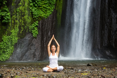 woman meditating doing yoga between waterfallsの写真素材