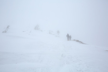 Backpacker walk in strond thunderstorm in winter mountains の写真素材