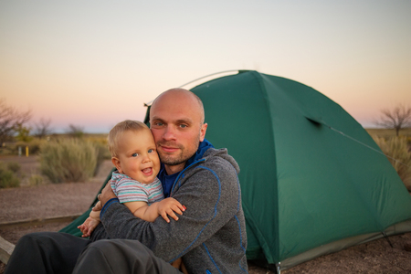 A father plays with his baby son at the tent in campground of Homolovi State Parkの写真素材