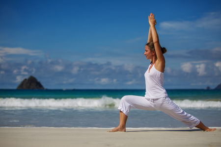 Caucasian woman practicing yoga at seashore of tropic oceanの写真素材