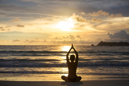 Caucasian woman practicing yoga at seashore of tropic oceanの写真素材