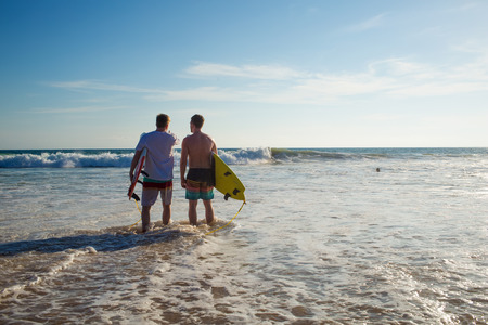 Two men with a surfboard on the beachの写真素材