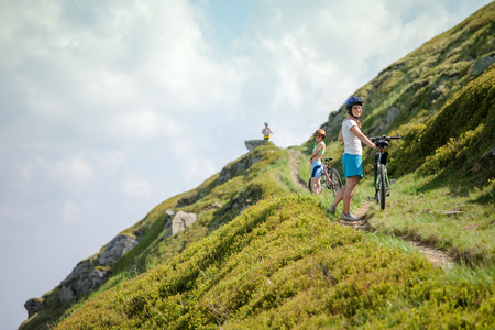 Biker pushes bicycle up in the mountainsの写真素材
