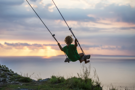 The back of the boys Swings are playing on the beachの写真素材
