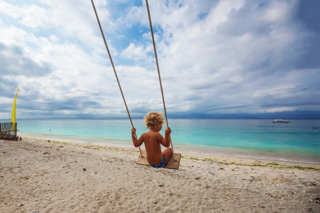 The back of the boys Swings are playing on the beachの写真素材
