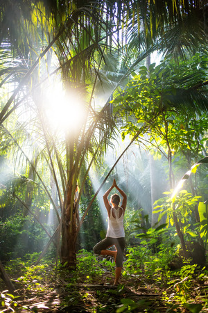 woman doing yoga outside in jungleの写真素材