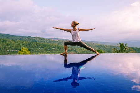 Caucasian woman practicing yoga by the poolの写真素材