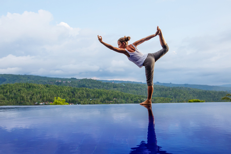 Caucasian woman practicing yoga by the poolの写真素材
