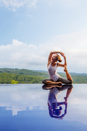 Caucasian woman practicing yoga by the poolの写真素材