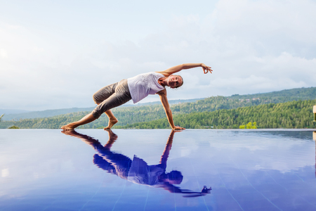 Caucasian woman practicing yoga by the poolの写真素材