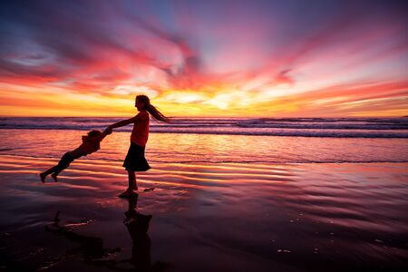 mother and son having fun at sunset on the beachの写真素材