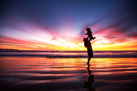 mother and son having fun at sunset on the beachの写真素材