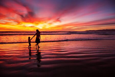 mother and son having fun at sunset on the beachの写真素材