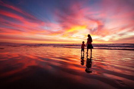 mother and son having fun at sunset on the beachの写真素材