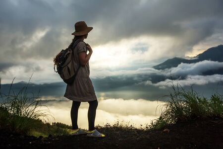 Woman enjoying sunrise from a top of mountain Batur, Bali, Indonesia.の写真素材