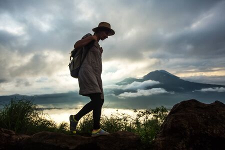 Woman enjoying sunrise from a top of mountain Batur, Bali, Indonesia.の写真素材