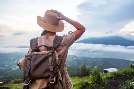 Woman enjoying sunrise from a top of mountain Batur, Bali, Indonesia.の写真素材